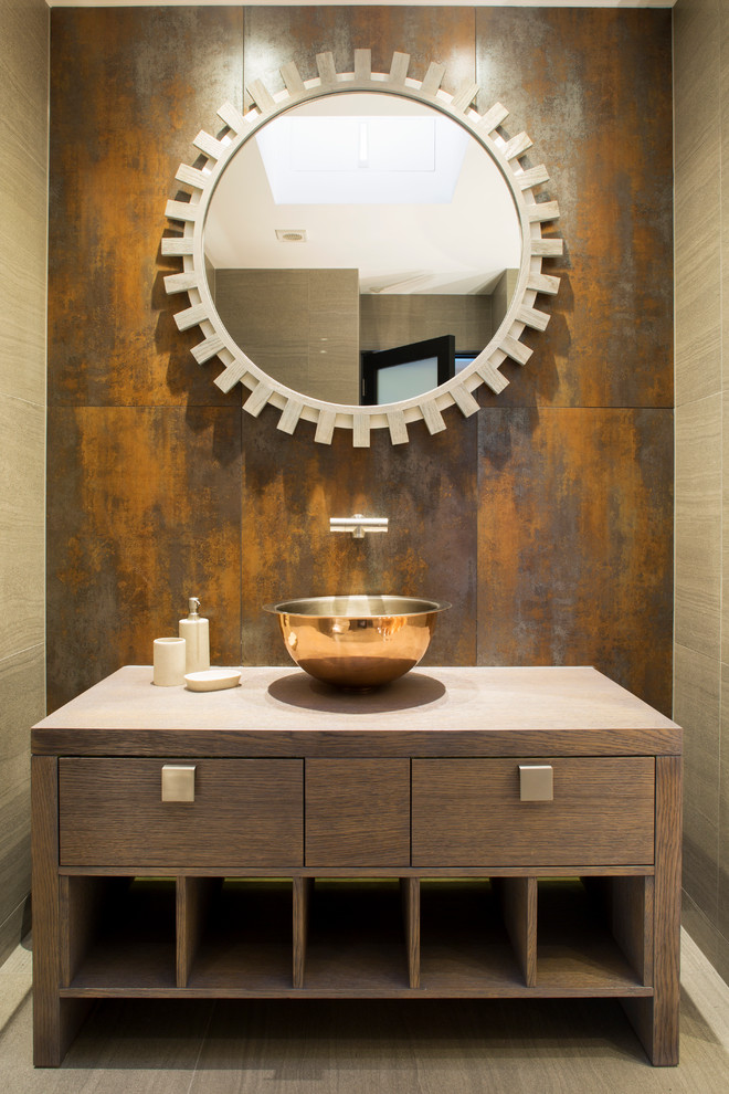 Example of a trendy powder room design in London with a vessel sink, furniture-like cabinets, medium tone wood cabinets, wood countertops and brown countertops