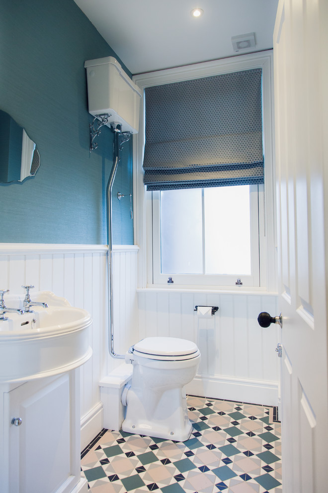 Klassische Gästetoilette mit Wandtoilette mit Spülkasten, blauer Wandfarbe, Zementfliesen für Boden, Waschtischkonsole und buntem Boden in Sonstige