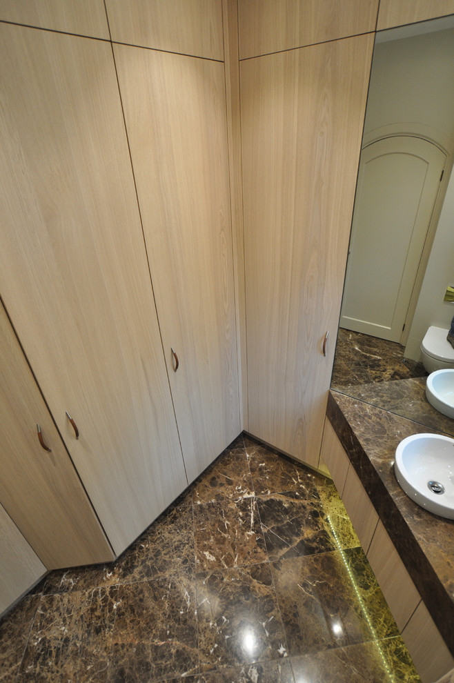 This is an example of a small contemporary cloakroom in London with flat-panel cabinets, light wood cabinets, a wall mounted toilet, beige tiles, beige walls, marble flooring, an integrated sink, marble worktops, brown floors and brown worktops.
