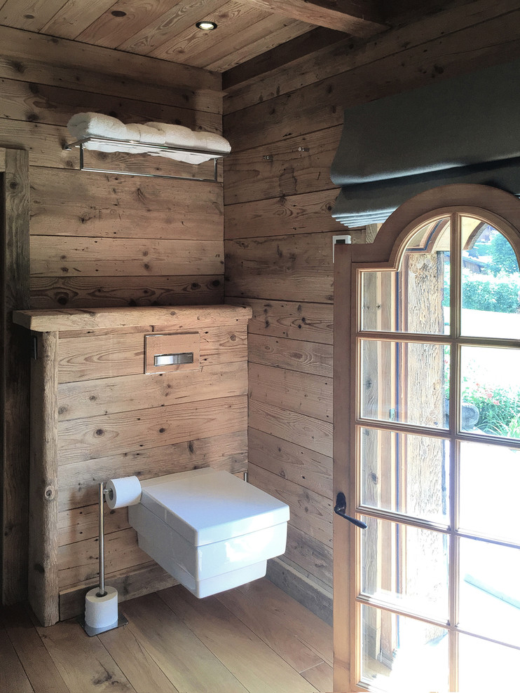 Inspiration pour un WC suspendu chalet en bois brun de taille moyenne avec un lavabo intégré, un placard à porte plane et un sol en bois brun.