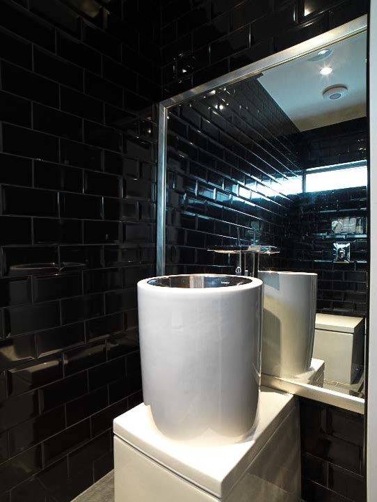 Esempio di un bagno di servizio minimal di medie dimensioni con WC monopezzo, piastrelle nere, piastrelle in ceramica, pareti nere, pavimento con piastrelle in ceramica e lavabo a bacinella