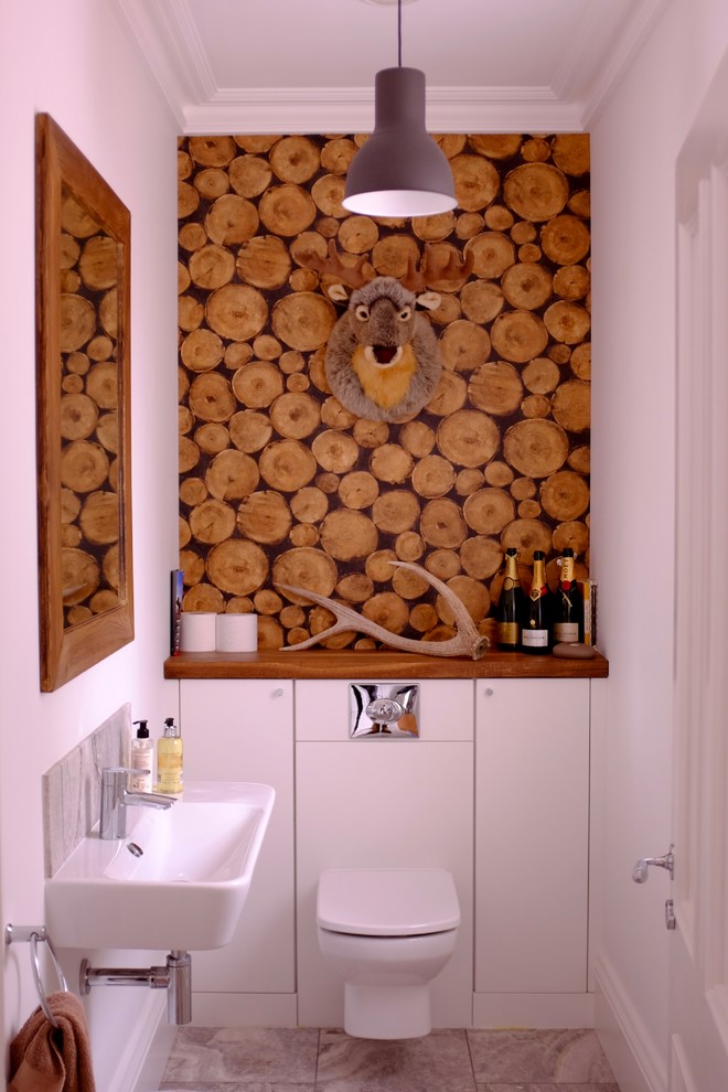 ハンプシャーにあるラスティックスタイルのおしゃれなトイレ・洗面所 (フラットパネル扉のキャビネット、白いキャビネット、壁掛け式トイレ、グレーのタイル、白い壁、壁付け型シンク、木製洗面台、グレーの床) の写真