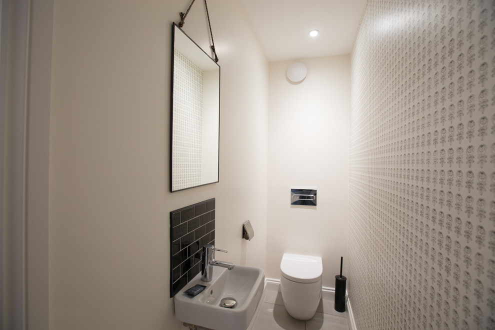 Idee per un piccolo bagno di servizio scandinavo con WC monopezzo, piastrelle nere, piastrelle in ceramica, pareti bianche, pavimento in linoleum e lavabo sospeso