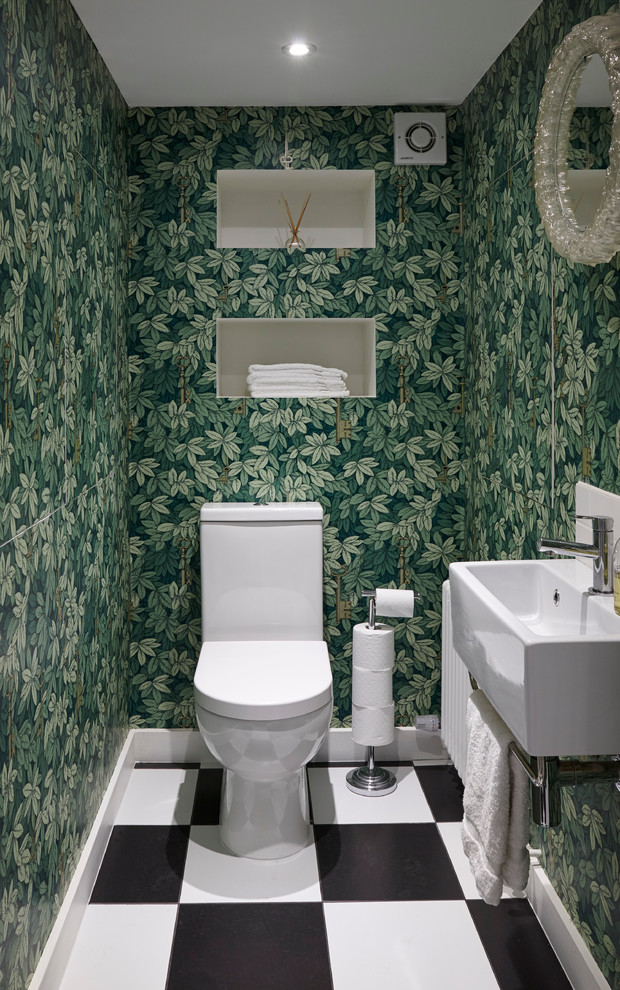 Bild på ett mellanstort eklektiskt toalett, med en toalettstol med hel cisternkåpa, gröna väggar, linoleumgolv, ett väggmonterat handfat och svart och vit kakel