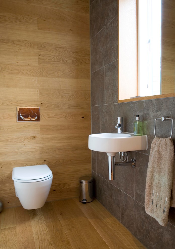 Small trendy porcelain tile and gray tile light wood floor powder room photo in Edinburgh with a wall-mount sink and a wall-mount toilet