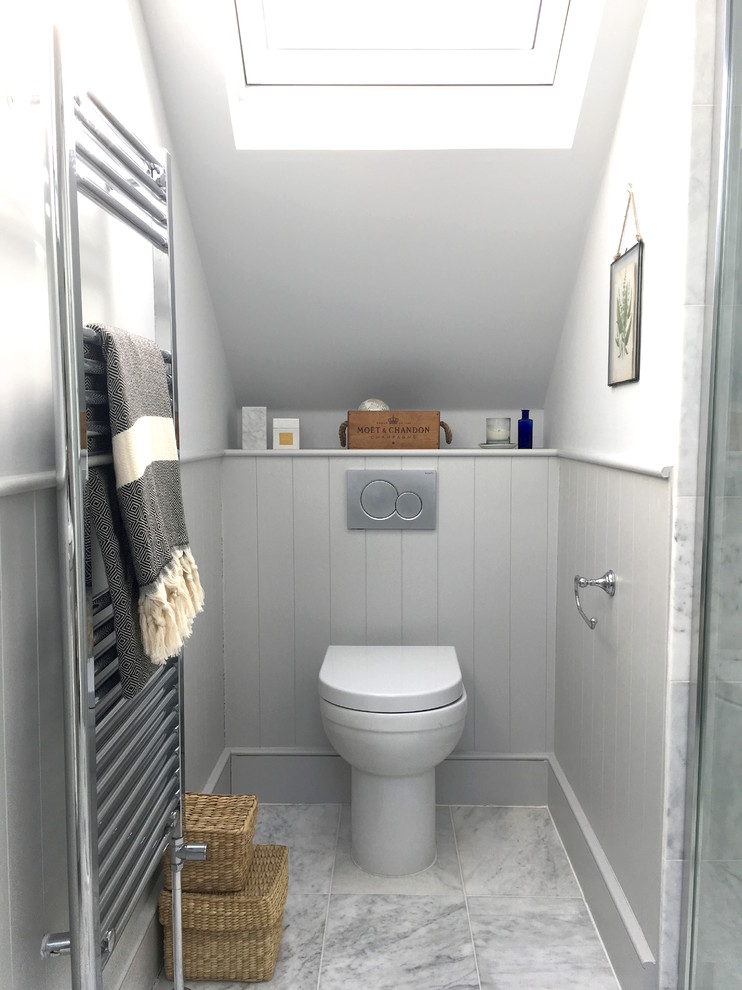 Klassisk inredning av ett litet toalett, med en toalettstol med hel cisternkåpa, vita väggar, marmorgolv och grått golv