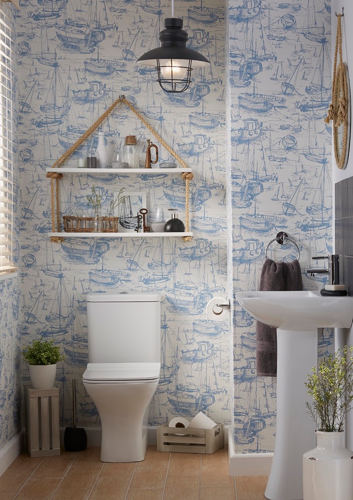 Bild på ett litet maritimt toalett, med en toalettstol med hel cisternkåpa, grå kakel, orange kakel, porslinskakel, blå väggar, klinkergolv i keramik och ett piedestal handfat