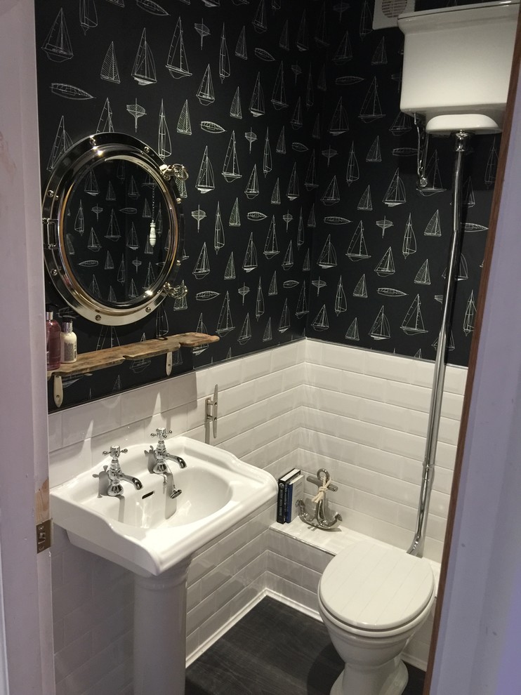 This is an example of a small coastal cloakroom in Other with a two-piece toilet, white tiles, black tiles, black walls and a pedestal sink.
