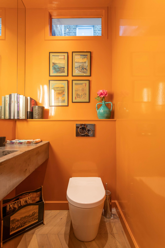 Moderne Gästetoilette mit oranger Wandfarbe, braunem Holzboden, integriertem Waschbecken, Waschtisch aus Holz, braunem Boden und brauner Waschtischplatte in London