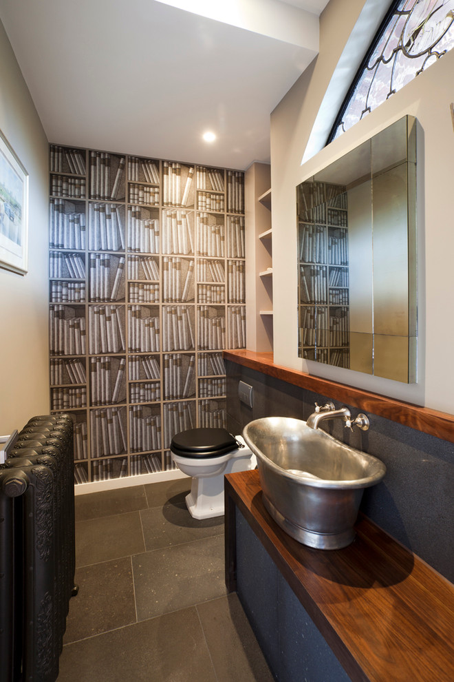 Immagine di un bagno di servizio bohémian di medie dimensioni con lavabo a bacinella, top in legno, WC monopezzo, pareti multicolore e top marrone
