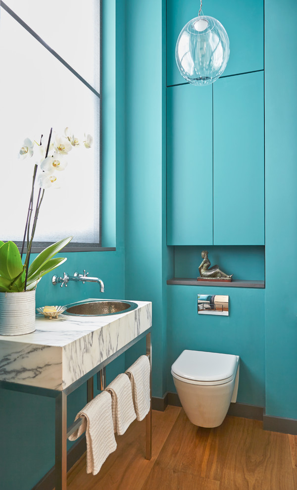 Idées déco pour un WC suspendu classique avec un mur bleu, un sol en bois brun et un lavabo posé.