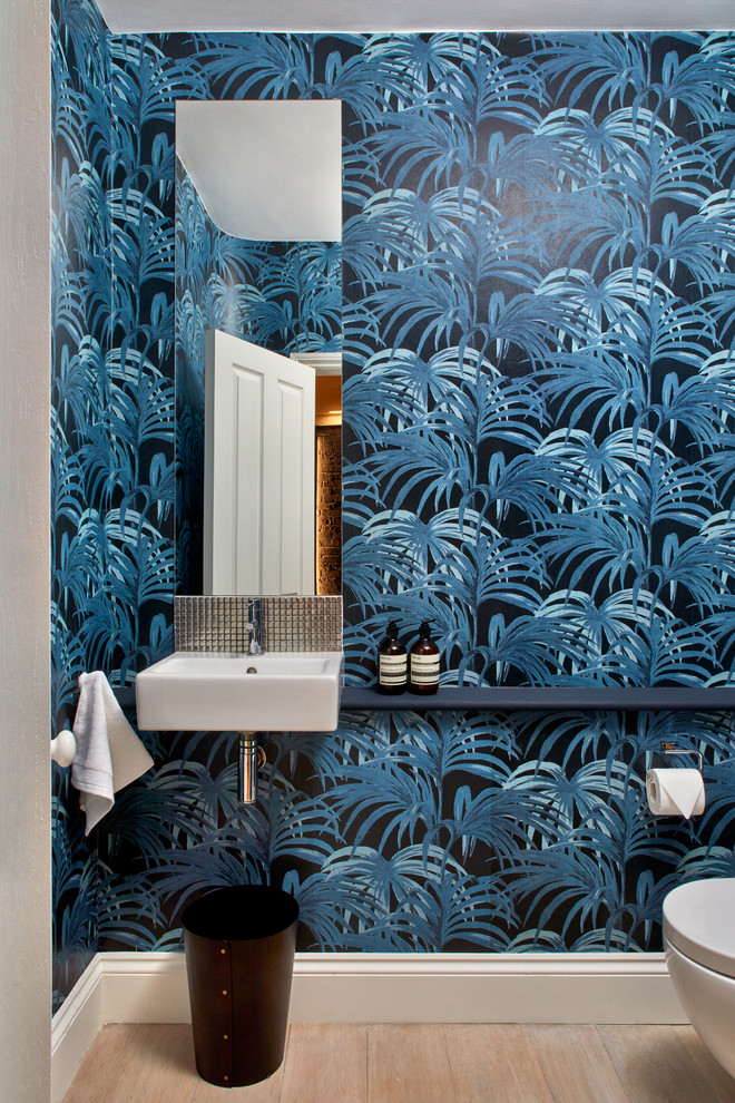 Kleine Moderne Gästetoilette mit Wandtoilette, blauer Wandfarbe, hellem Holzboden, offenen Schränken, Wandwaschbecken, Waschtisch aus Holz, beigem Boden und blauer Waschtischplatte in London