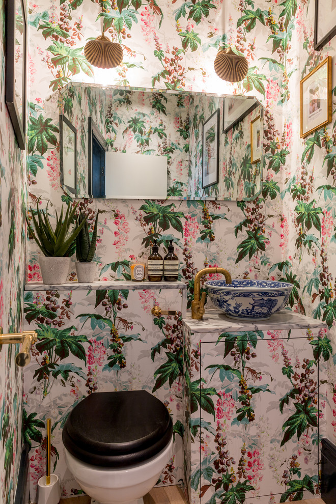 Große Stilmix Gästetoilette mit flächenbündigen Schrankfronten, Toilette mit Aufsatzspülkasten, bunten Wänden, braunem Holzboden, gefliestem Waschtisch, braunem Boden und Aufsatzwaschbecken in London