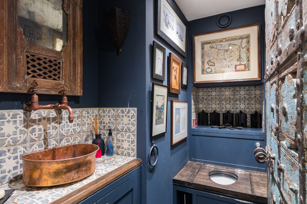 Kleine Mediterrane Gästetoilette mit farbigen Fliesen, blauen Schränken, blauer Wandfarbe, Aufsatzwaschbecken, gefliestem Waschtisch, Toilette mit Aufsatzspülkasten und bunter Waschtischplatte in London