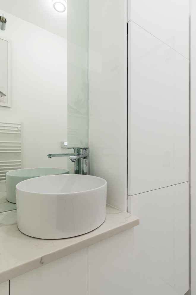 This is an example of a small contemporary cloakroom in London with flat-panel cabinets, white cabinets, a wall mounted toilet, white walls, a vessel sink, marble worktops, white tiles, porcelain flooring, grey floors and grey worktops.