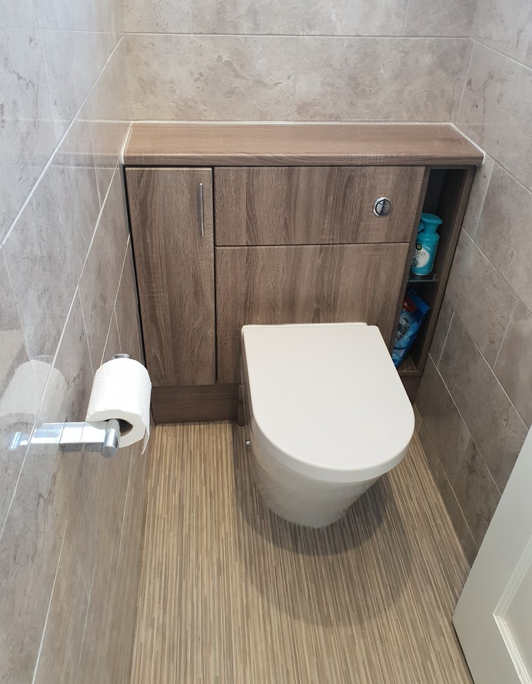 Cette image montre un petit WC et toilettes minimaliste en bois brun avec un placard à porte plane, WC à poser, un carrelage gris, des carreaux de céramique, un sol en vinyl, un plan de toilette en stratifié, un sol multicolore et un plan de toilette marron.