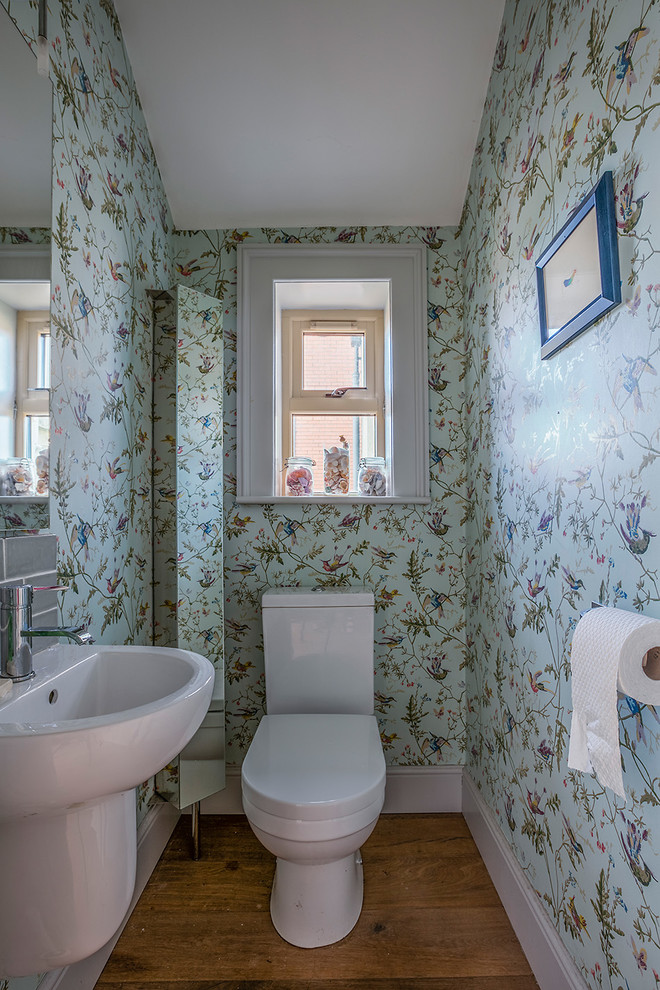 Idées déco pour un petit WC et toilettes classique avec WC à poser, un mur multicolore et parquet foncé.