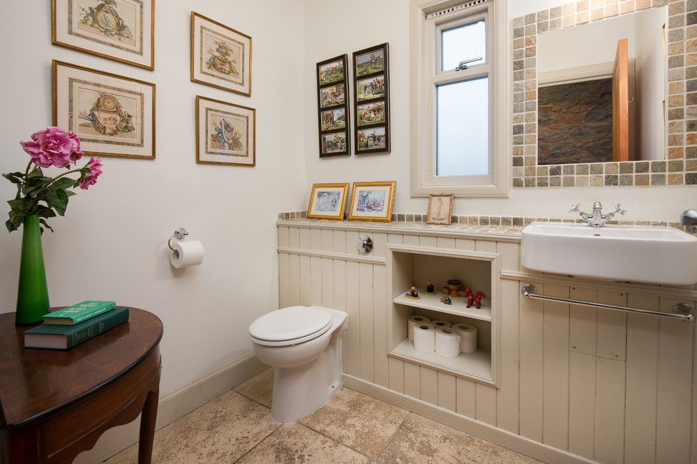 Mittelgroße Landhaus Gästetoilette mit Toilette mit Aufsatzspülkasten, weißer Wandfarbe, beigem Boden, beigen Schränken, Keramikboden, gefliestem Waschtisch und offenen Schränken in Sonstige