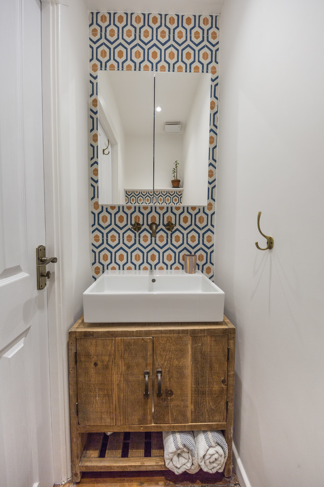 Inspiration for a mediterranean cloakroom in London with flat-panel cabinets, medium wood cabinets, blue tiles, orange tiles, white tiles, white walls and a vessel sink.