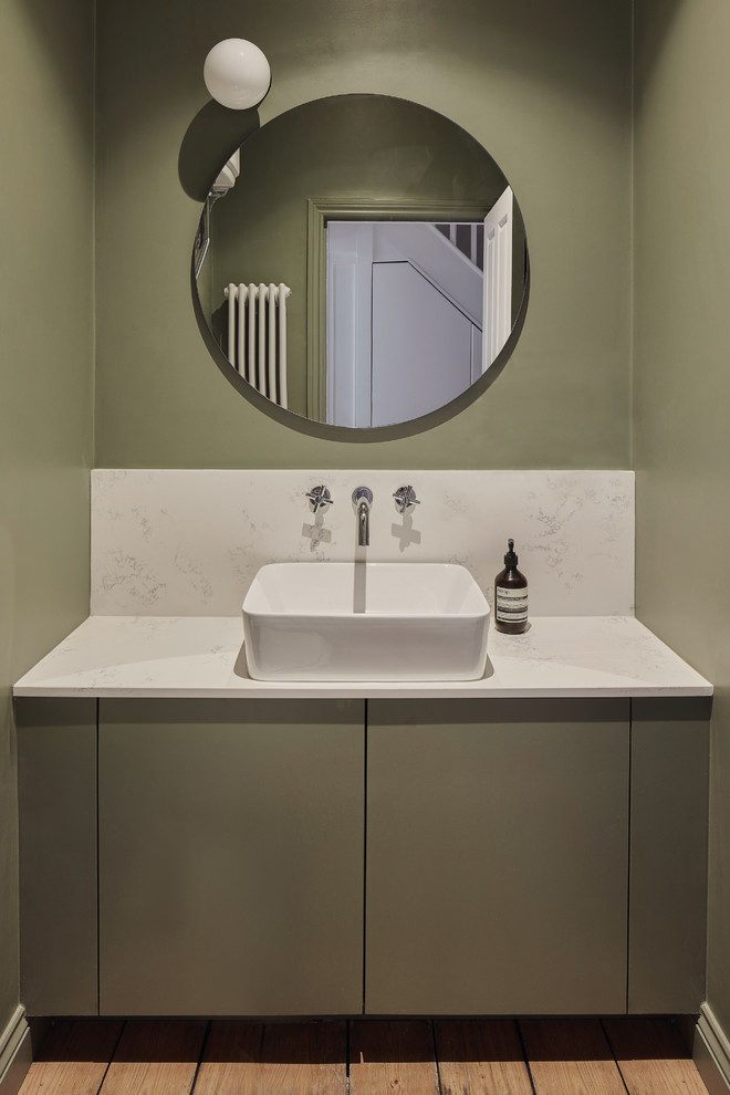 Immagine di un bagno di servizio scandinavo con ante lisce, ante verdi, pareti verdi, pavimento in legno massello medio, lavabo a bacinella e top bianco