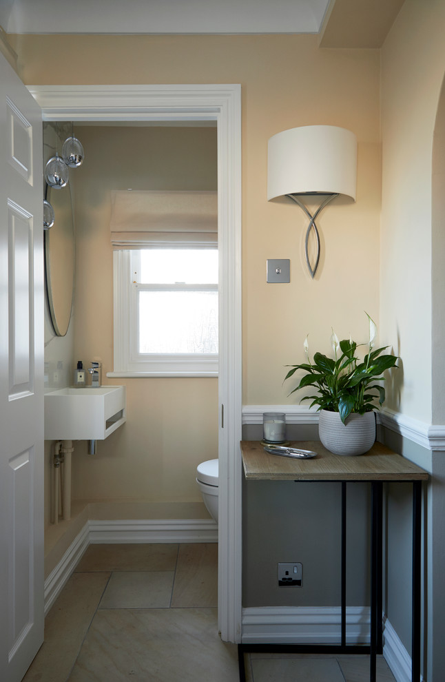 Réalisation d'un petit WC suspendu design avec des portes de placard blanches, un carrelage gris, du carrelage en marbre, un mur beige, un sol en calcaire, un lavabo suspendu, un plan de toilette en surface solide et un sol beige.