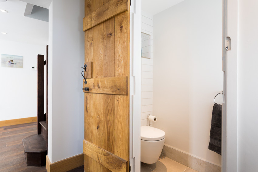 Small rustic cloakroom in Kent with open cabinets, dark wood cabinets, a wall mounted toilet, white tiles, metro tiles, white walls, ceramic flooring, a vessel sink, wooden worktops, beige floors, brown worktops and a floating vanity unit.