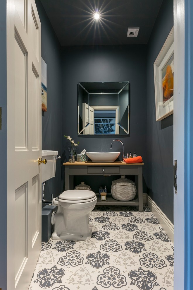 Inspiration pour un WC et toilettes design de taille moyenne avec un placard sans porte, des portes de placard grises, WC séparés, un mur gris, carreaux de ciment au sol, un plan de toilette en bois, un sol multicolore et un plan de toilette marron.