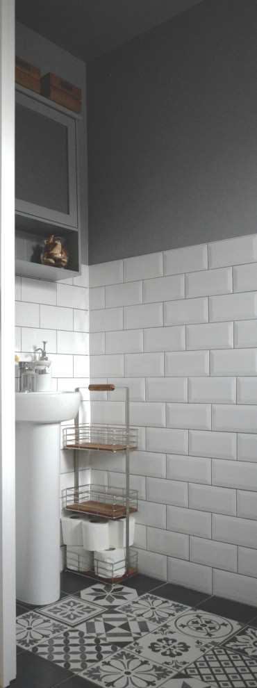 Cette image montre un petit WC et toilettes nordique avec WC à poser, un carrelage blanc, des carreaux de céramique, un mur gris, un sol en carrelage de céramique, un sol multicolore et meuble-lavabo sur pied.