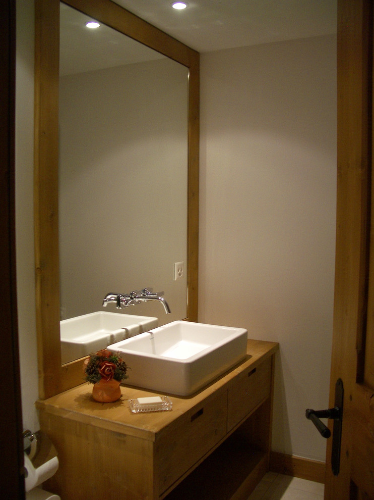 Immagine di un bagno di servizio chic di medie dimensioni con lavabo rettangolare, ante in legno chiaro, pavimento in pietra calcarea, pareti bianche, top in legno e pavimento bianco