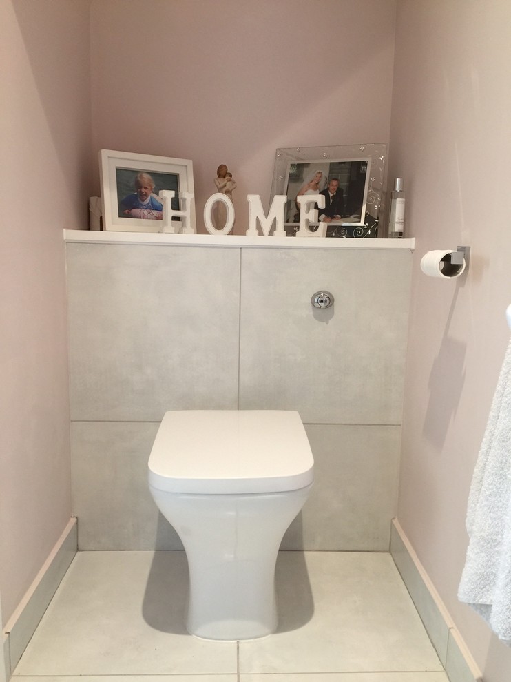 Foto på ett litet funkis toalett, med en toalettstol med hel cisternkåpa, vit kakel, porslinskakel och klinkergolv i porslin