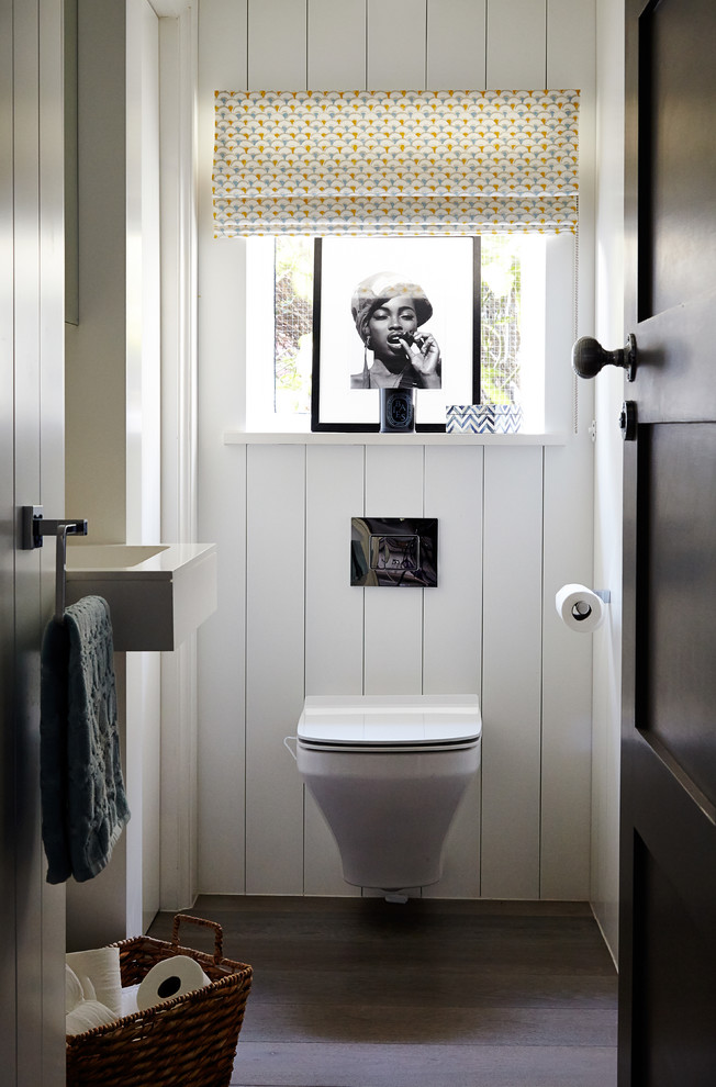 Idéer för vintage toaletter, med ett väggmonterat handfat, vita väggar, mörkt trägolv och en vägghängd toalettstol