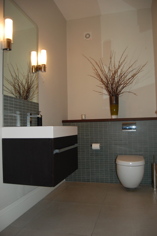 Idéer för ett mellanstort modernt toalett, med ett väggmonterat handfat, möbel-liknande, skåp i mörkt trä, bänkskiva i kvarts, en vägghängd toalettstol, grå kakel, keramikplattor och grå väggar