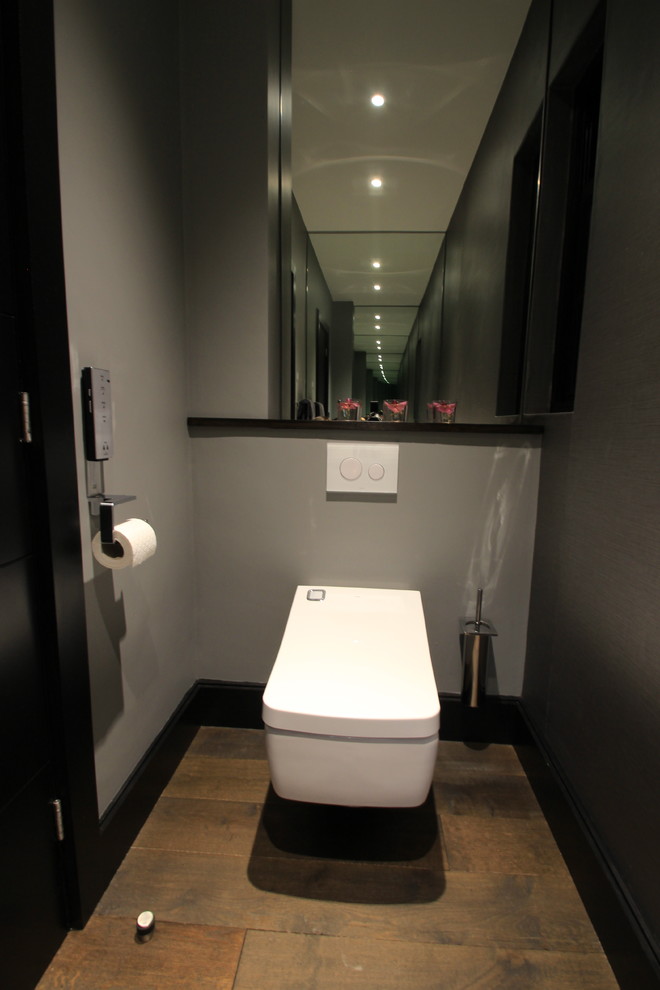 Ispirazione per un piccolo bagno di servizio minimalista con ante lisce, ante in legno bruno, WC sospeso, pareti grigie e lavabo a bacinella