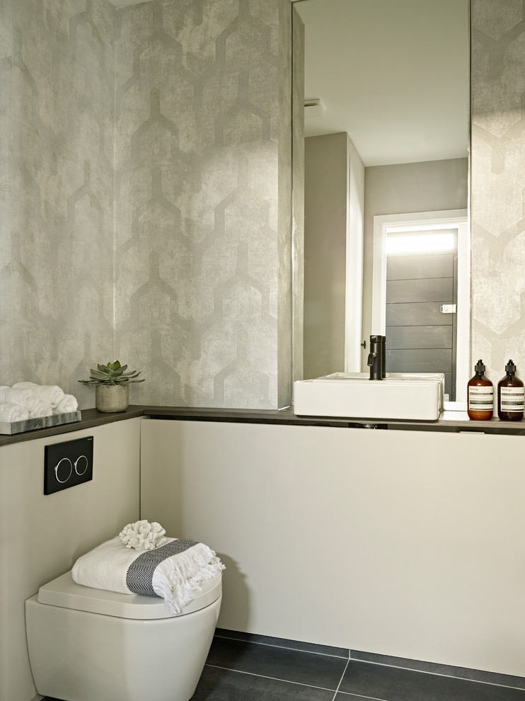 Immagine di un piccolo bagno di servizio minimal con WC sospeso, piastrelle nere, pareti grigie, pavimento in gres porcellanato, top in laminato, pavimento nero e top nero