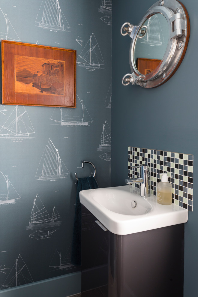 Kleine Maritime Gästetoilette mit flächenbündigen Schrankfronten, grauen Schränken, blauen Fliesen, weißen Fliesen, blauer Wandfarbe, integriertem Waschbecken und weißer Waschtischplatte in Sussex