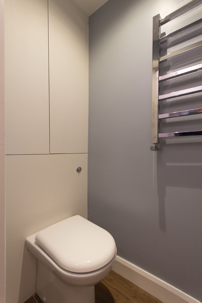 Small modern cloakroom in London with flat-panel cabinets, white cabinets, a one-piece toilet, brown tiles, ceramic tiles, blue walls, porcelain flooring and a built-in sink.