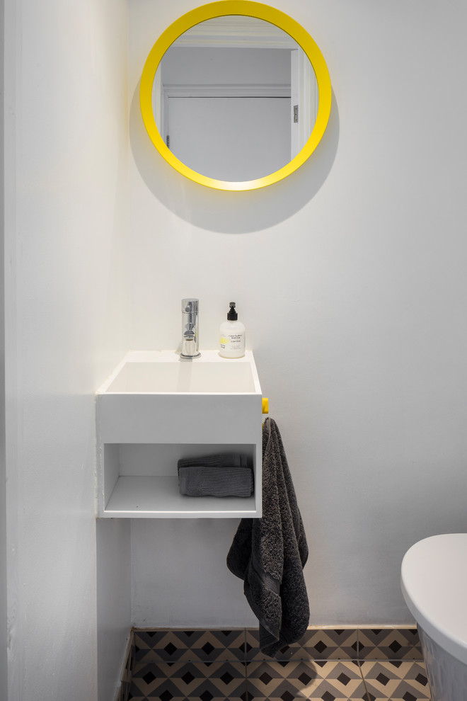 Photo of a small contemporary cloakroom in London with open cabinets, white cabinets, a wall mounted toilet, white walls, porcelain flooring, an integrated sink and grey floors.