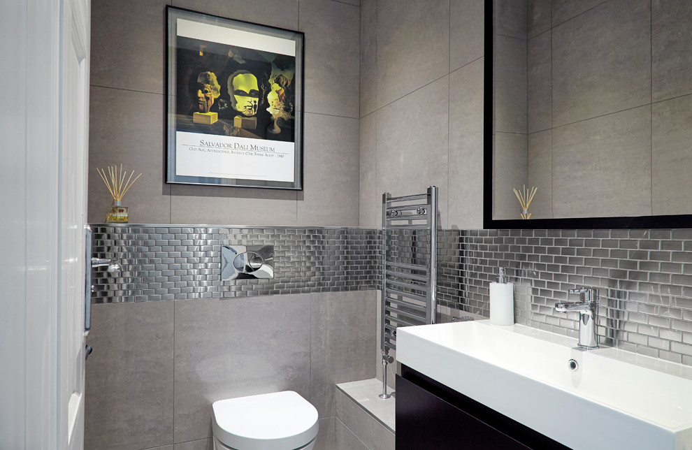 Пример оригинального дизайна: туалет среднего размера в современном стиле с инсталляцией, серой плиткой, серыми стенами и раковиной с несколькими смесителями