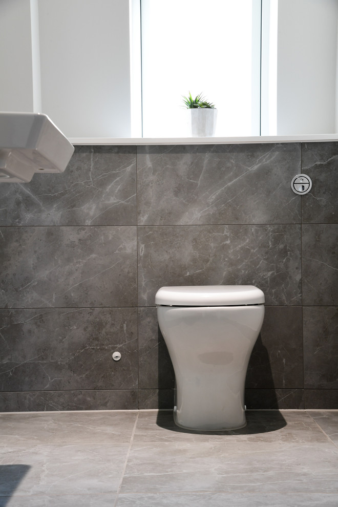 Aménagement d'un WC et toilettes contemporain avec un carrelage gris, des carreaux de porcelaine, un sol en carrelage de porcelaine et un sol gris.