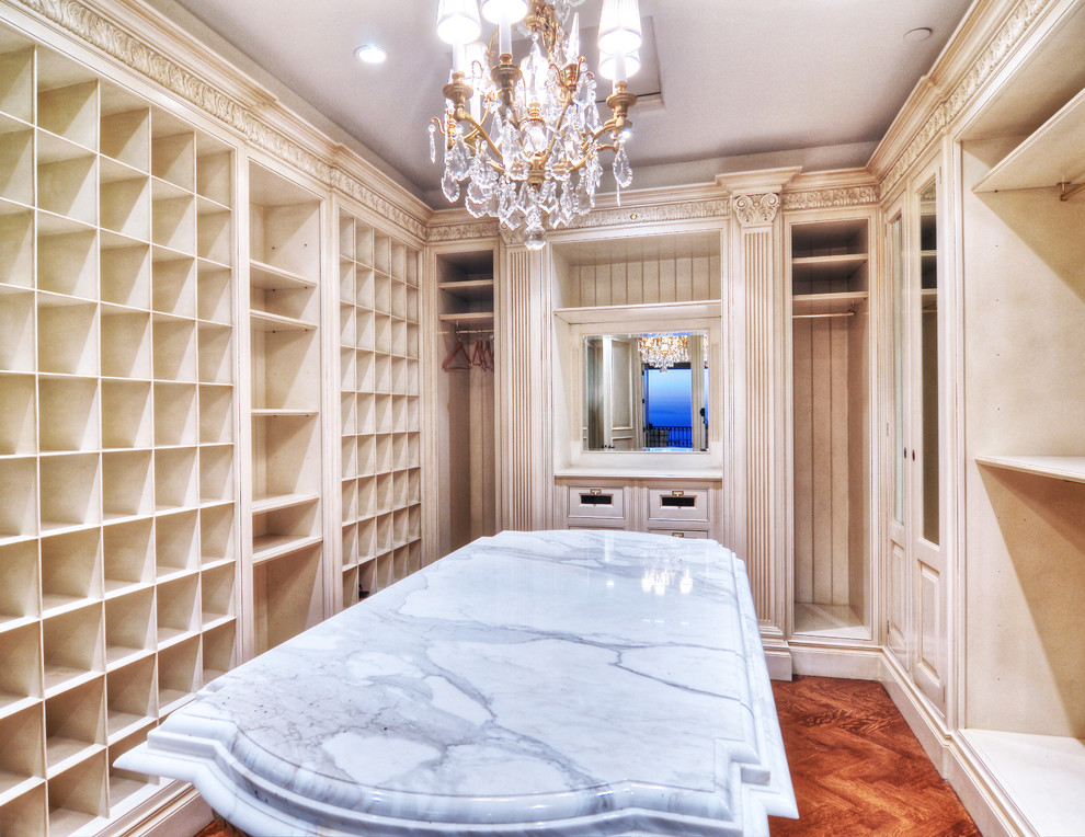 Diseño de armario vestidor unisex mediterráneo extra grande con armarios abiertos, puertas de armario beige y suelo de madera en tonos medios