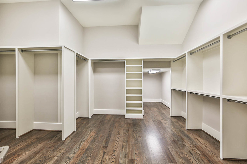This is an example of an expansive classic gender neutral walk-in wardrobe in Houston with dark hardwood flooring.