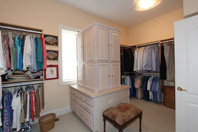Ejemplo de vestidor unisex clásico renovado de tamaño medio con puertas de armario de madera clara y moqueta
