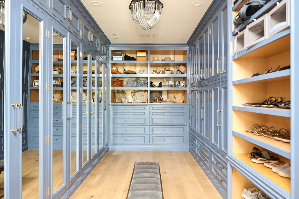 Expansive traditional walk-in wardrobe for women in Los Angeles with recessed-panel cabinets, blue cabinets, light hardwood flooring and beige floors.