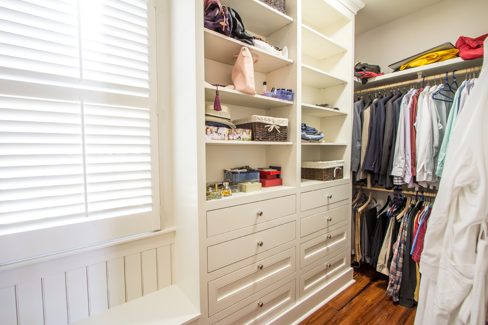 Example of a large classic gender-neutral medium tone wood floor walk-in closet design in New Orleans with flat-panel cabinets and white cabinets