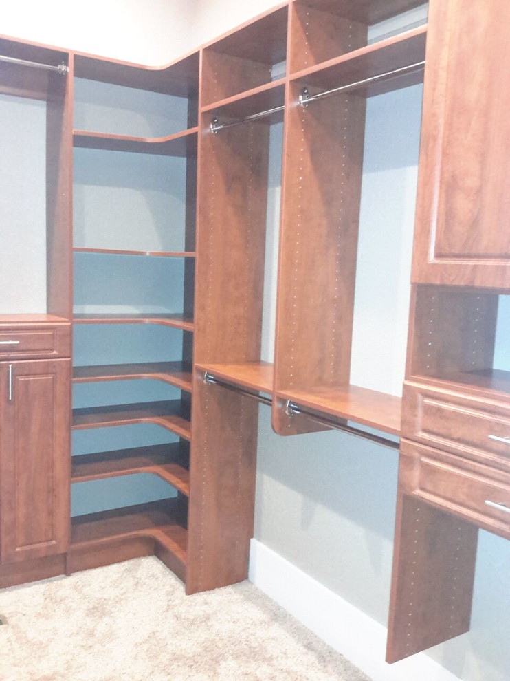 Foto de armario vestidor unisex clásico grande con armarios con paneles con relieve, puertas de armario de madera oscura y moqueta