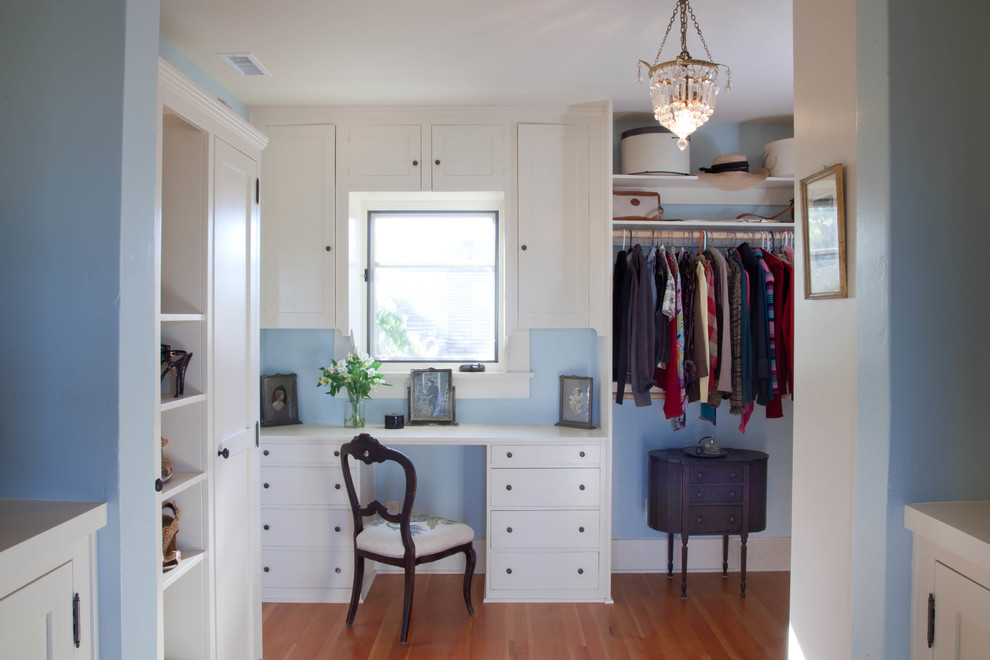 Idées déco pour un dressing room craftsman avec un placard à porte shaker, des portes de placard blanches et un sol en bois brun.