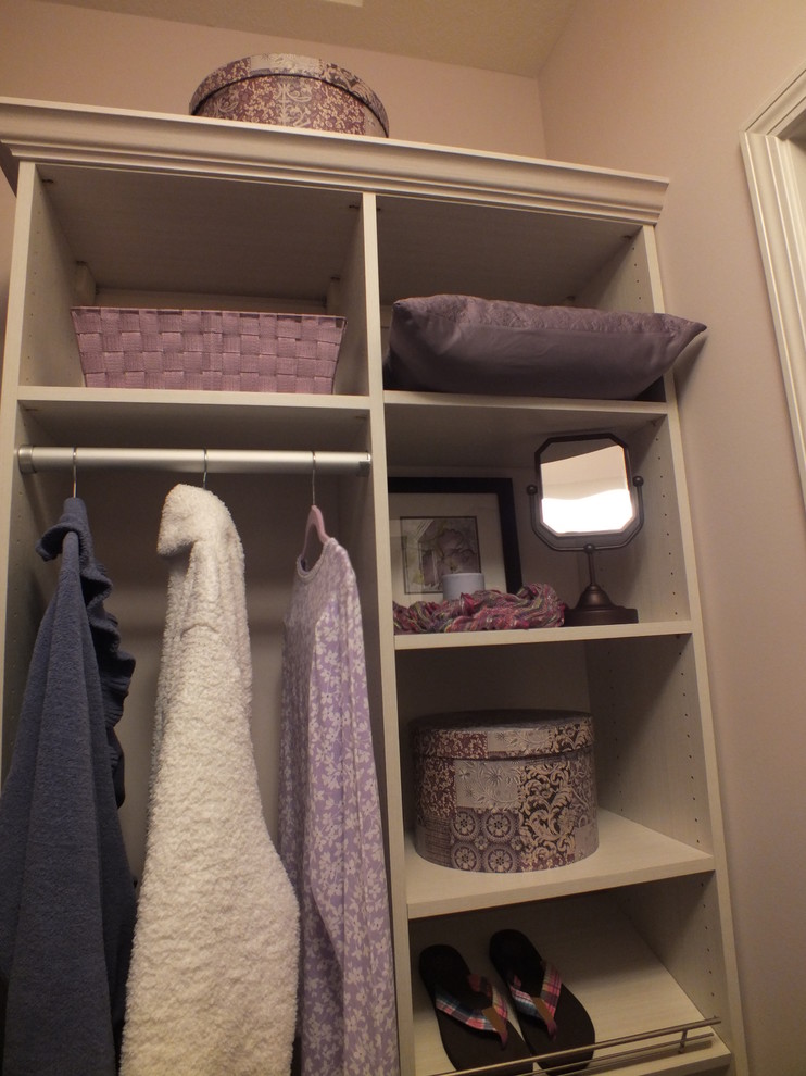 This is an example of a medium sized contemporary walk-in wardrobe for women in Cleveland with raised-panel cabinets and light wood cabinets.