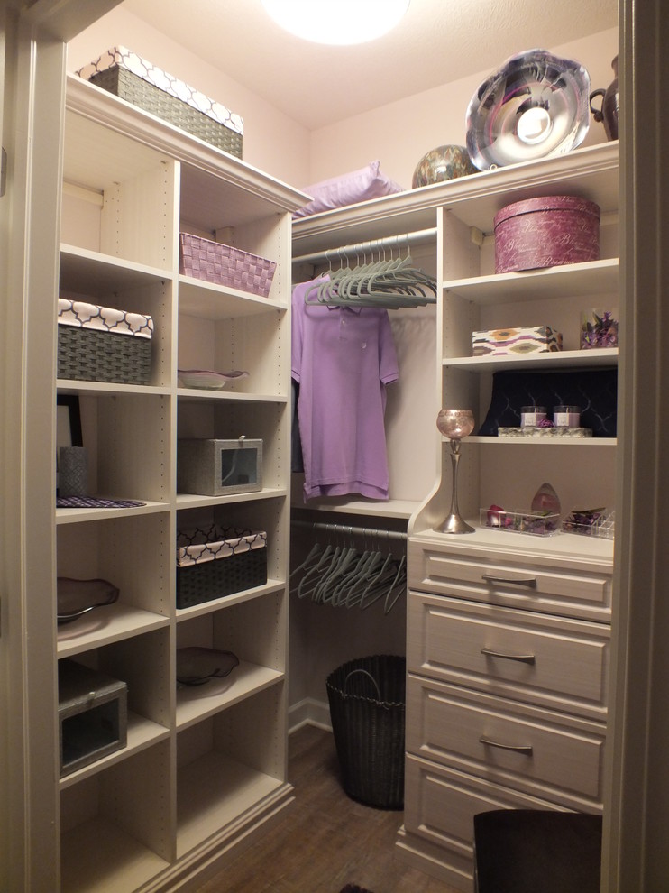 This is an example of a medium sized contemporary walk-in wardrobe for women in Cleveland with raised-panel cabinets and light wood cabinets.