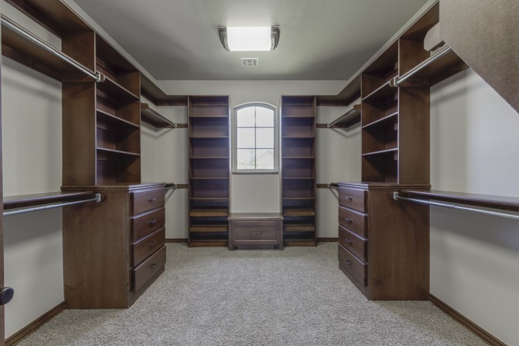 Large transitional gender-neutral carpeted walk-in closet photo in Oklahoma City with shaker cabinets and dark wood cabinets