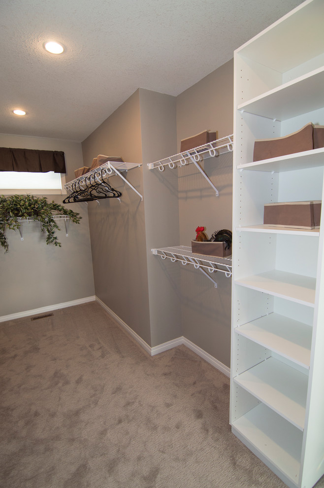 This is an example of a large contemporary gender neutral walk-in wardrobe in Calgary with open cabinets, carpet and white cabinets.